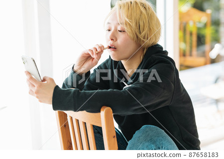 A woman brushing her teeth while looking at her smartphone A woman brushing her teeth while looking at her smartphone 87658183