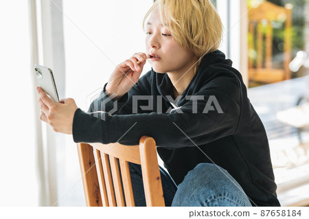 A woman brushing her teeth while looking at her smartphone 87658184