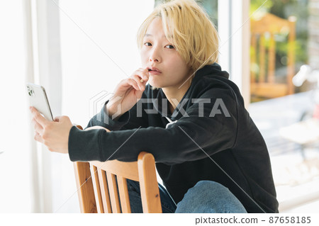 A woman brushing her teeth while holding a smartphone 87658185