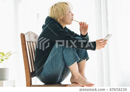 A woman brushing her teeth while holding a smartphone 87658230