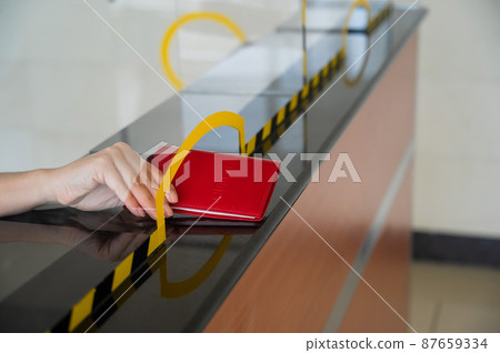 An airport employee at the check-in counter takes the passenger's passport. 87659334