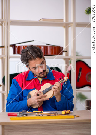Young man repairing musical instruments at workshop Young man repairing musical instruments at workshop 87659505