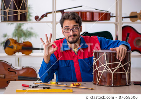 Young man repairing musical instruments at workshop Young man repairing musical instruments at workshop 87659506
