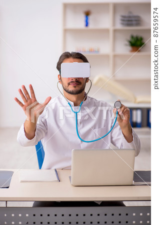 Young male doctor wearing virtual glasses Young male doctor wearing virtual glasses 87659574