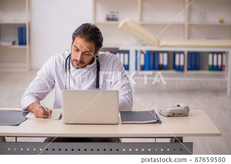 Young male doctor working in the clinic Young male doctor working in the clinic 87659580