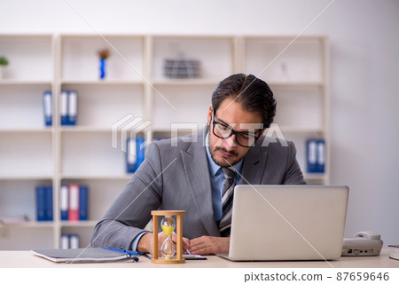 Young male employee in time management concept Young male employee in time management concept 87659646