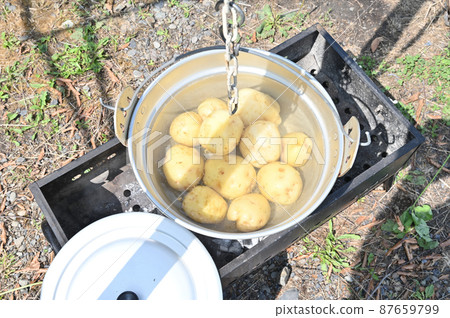 Potatoes steamed in a silver pot at the campsite 87659799