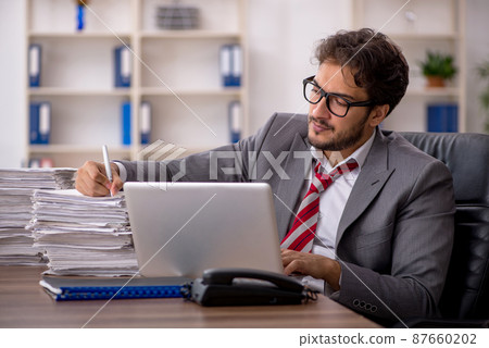 Young male employee unhappy with excessive work in the office 87660202