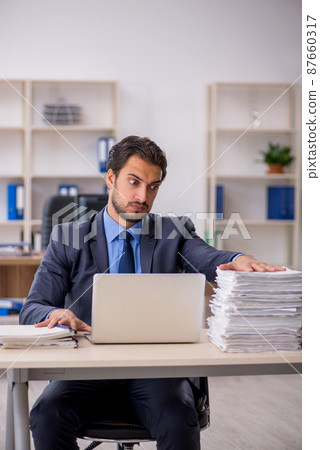 Young male employee and too much work in the office 87660317