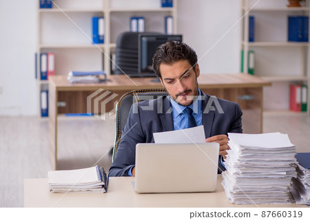 Young male employee and too much work in the office 87660319