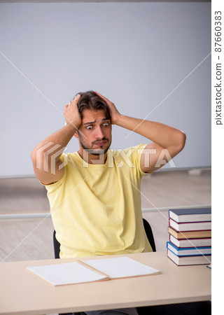 Young male student preparing for exams in the classroom Young male student preparing for exams in the classroom 87660383