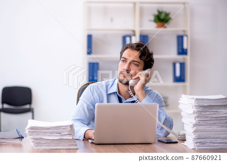 Young male employee and too much work in the office 87660921