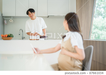 A man doing housework with a pregnant woman who feels fetal movement 87661034