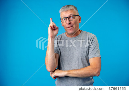 Senior man has a good idea, point finger up on blue background 87661363