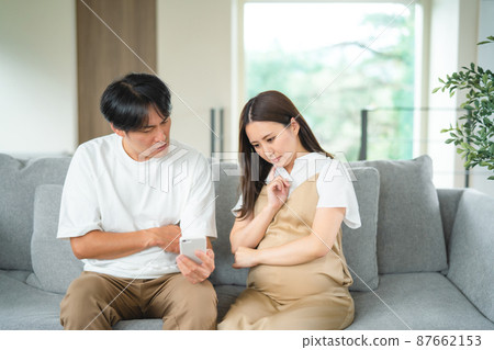 Pregnant women and men looking at smartphones (worried) 87662153