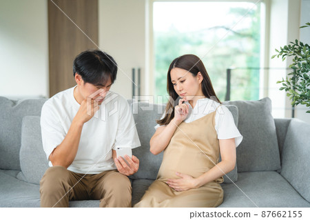 Pregnant women and men looking at smartphones (worried) 87662155