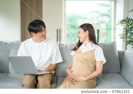 Pregnant women and men looking at a computer (smiles) Pregnant women and men looking at a computer (smiles) 87662161