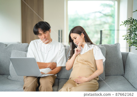 Pregnant women and men looking at a computer (worried) Pregnant women and men looking at a computer (worried) 87662162
