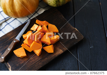Cut pieces of raw pumpkin on wooden board on table 87662375