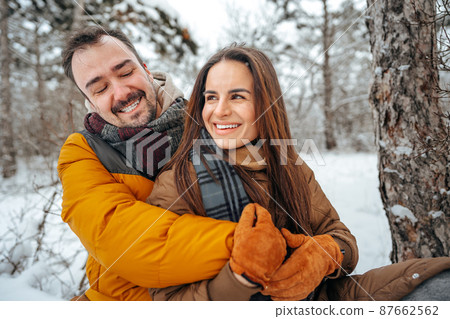Young couple in love outdoor in snowy winter forest. 87662562