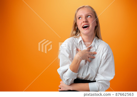 Portrait of smiling young teen girl against orange background 87662563