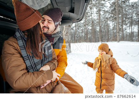 Lovely smiling couple sitting in car trunk in winter forest 87662614
