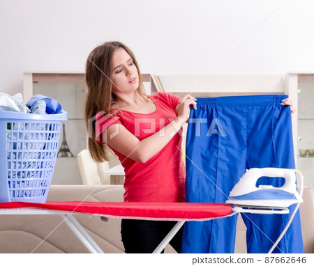 The young beautiful woman ironing at home 87662646