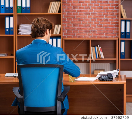 Young handsome employee sitting in the office Young handsome employee sitting in the office 87662709