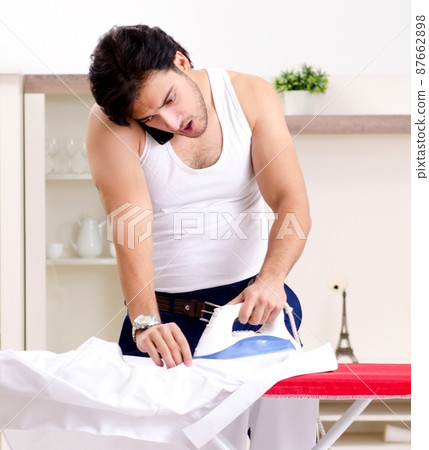 Young man ironing in the bedroom 87662898