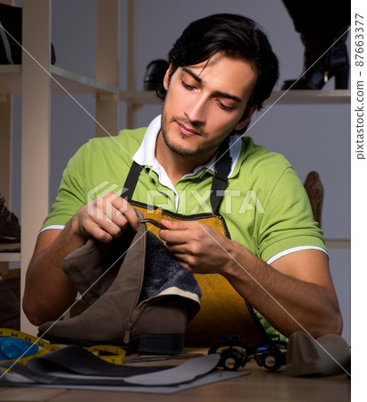 Young shoemaker in workshop at night Young shoemaker in workshop at night 87663377