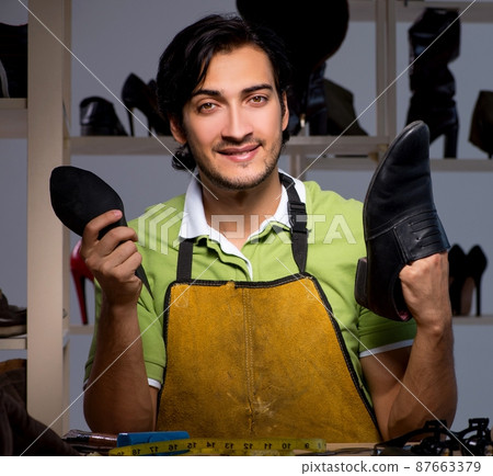 Young shoemaker in workshop at night 87663379