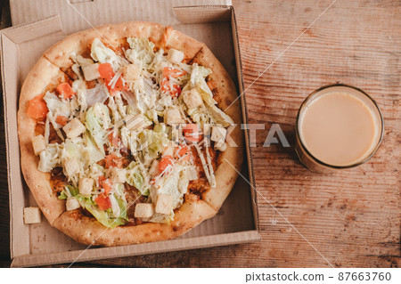 coffee drink in a transparent glass with caesar pizza on a wooden background. Cocoa and pizza, top view. coffee drink in a transparent glass with caesar pizza on a wooden background. Cocoa and pizza, top view. 87663760