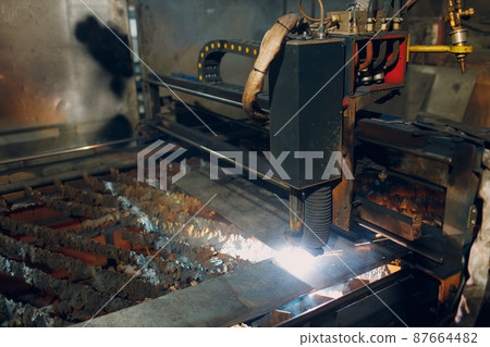 Automatic cnc laser cutting machine working with sheet metal with sparks. Metalworking industrial manufacturing factory. Automatic cnc laser cutting machine working with sheet metal with sparks. Metalworking industrial manufacturing factory. 87664482