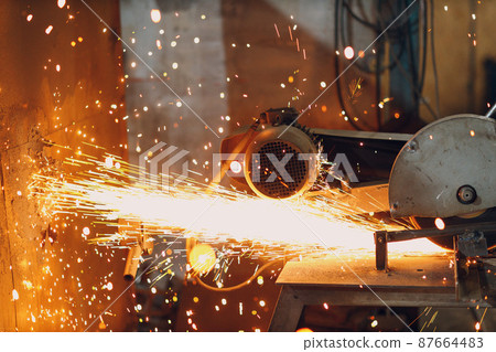 Metal processing with big compound mitre saw with circular blade. Sparks in metalworking at factory Metal processing with big compound mitre saw with circular blade. Sparks in metalworking at factory 87664483