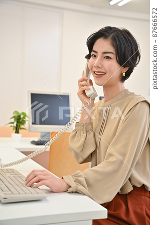 一個女人在辦公室打電話 一個女人在辦公室打電話 87666572