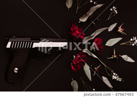 Flat lay for the world, on a black background gun and rose flowers, simulating a shot Flat lay for the world, on a black background gun and rose flowers, simulating a shot 87667483