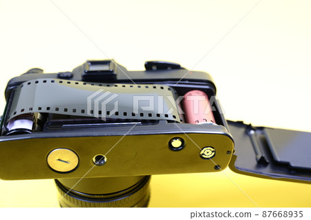 Open the back of the camera with the film roll attached. Focus on the film roll. 87668935