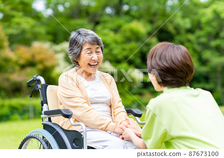 戶外輪椅的老年人和照顧他們的中級工作人員 87673100
