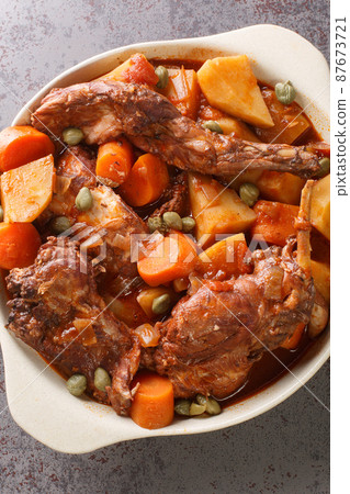Fenkata is the national dish of Malta, a communal meal that is prepared with rabbit as the star of the feast closeup in the pan. Vertical top view 87673721