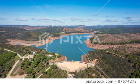 Aerial. Photo from sky, dams filled with water Bravura Portimao. in background, a park of wind generators for clean ecological electricity. Aerial. Photo from sky, dams filled with water Bravura Portimao. in background, a park of wind generators for clean ecological electricity. 87674272