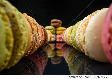 Colored macaroons confectionery marshmallows on a black reflective background in perspective. Extreme macro. 87674275