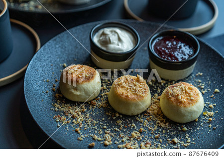 cottage cheese cheesecake in a black plate with sour cream and jam cottage cheese cheesecake in a black plate with sour cream and jam 87676409