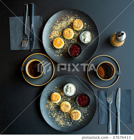cottage cheese cheesecake in a black plate with sour cream and jam 87676413