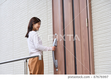 Woman opening the front door 87676997