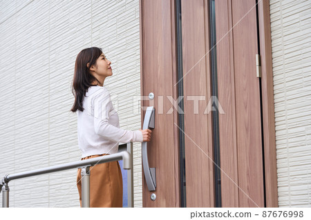 Woman opening the front door 87676998