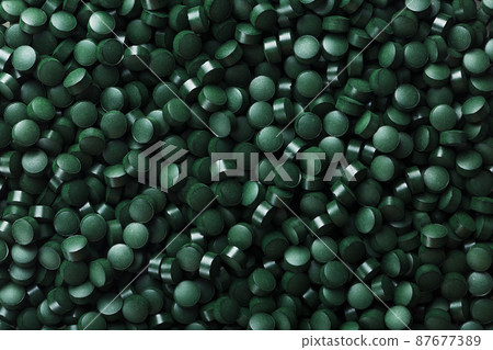 Dark Green round tablets of organic spirulina as a texture Dark Green round tablets of organic spirulina as a texture 87677389