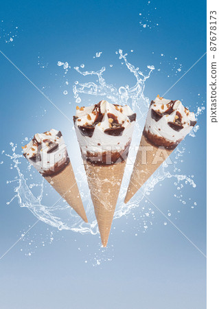 Flying ice cream cones with splash on blue background. Vertical format. Flying ice cream cones with splash on blue background. Vertical format. 87678173
