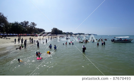 PORT DICKSON, MALAYSIA -MAY 09, 2021: Port Dickson beach is one of the famous tourist spots in Malaysia. Be the focus of people for recreation and water activities. PORT DICKSON, MALAYSIA -MAY 09, 2021: Port Dickson beach is one of the famous tourist spots in Malaysia. Be the focus of people for recreation and water activities. 87678493