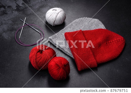 Red warm knitted women's hat on a concrete background Red warm knitted women's hat on a concrete background 87679751