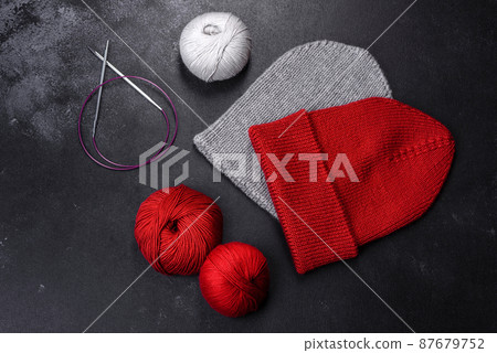 Red warm knitted women's hat on a concrete background Red warm knitted women's hat on a concrete background 87679752